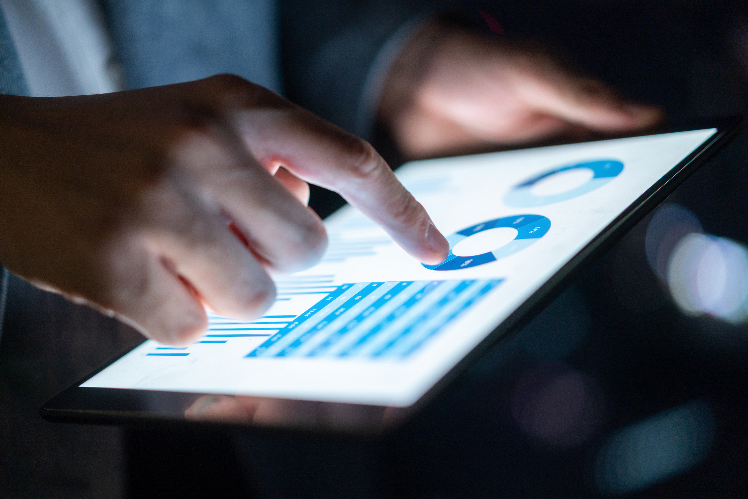 Hand interacting with graphs on a tablet screen